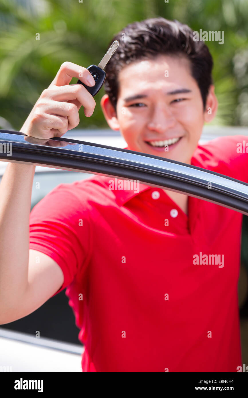 Asiatischer Mann zeigt Schlüssel seines neuen Autos Stockfoto