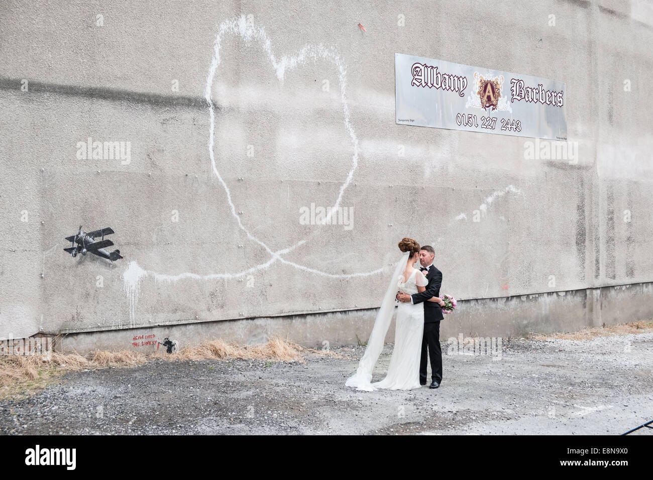 Hochzeit Bilder/Fotos von ein paar Vor einem Herzförmigen Vapor Trail aus bi-Ebene. Banksy, grafitti, Kunst, Liebe, Flugzeug, Liverpool, Stockfoto