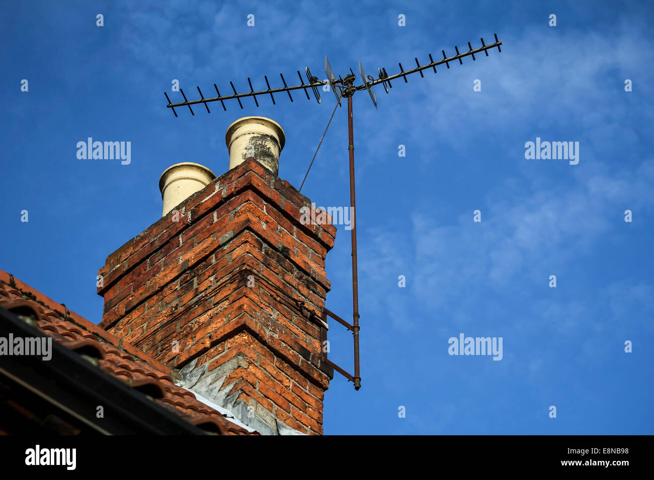Schornstein auf dem Dach eines Hauses mit terrestrischen DVB-t TV Antenne und blauer Himmel mit helle Wolke Stockfoto