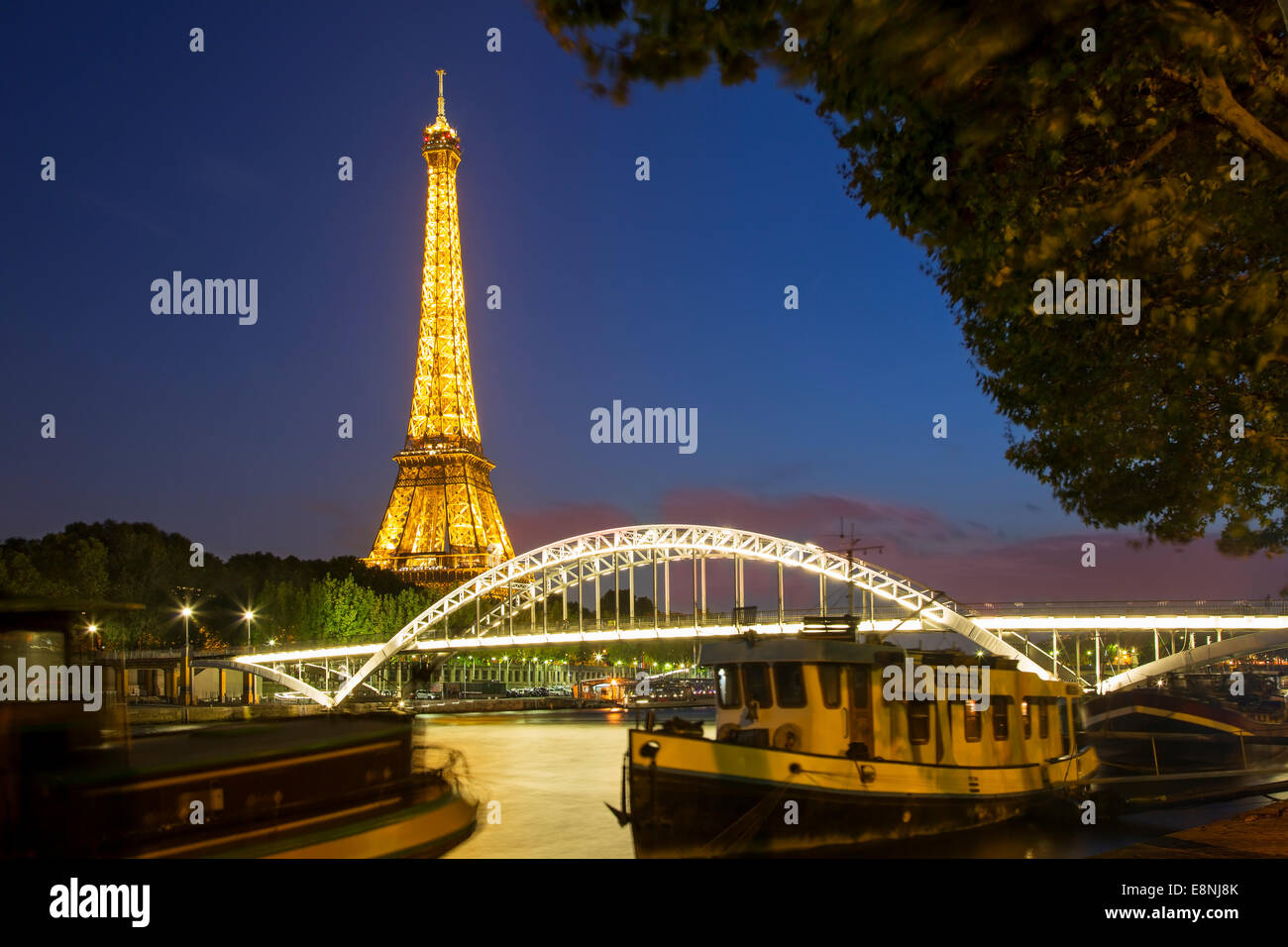 Dämmerung unter dem Eiffelturm, Flussschiffe und Fußgängerbrücke Passerelle Debilly entlang Seine, Paris, Frankreich Stockfoto