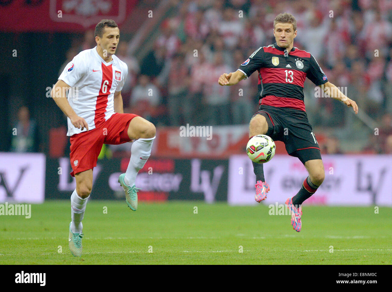 Warschau, Polen. 11. Oktober 2014. Polens Tomasz Jodlowiec (l) und Thomas Mueller Deutschland wetteifern um die Kugel während der der UEFA EURO 2016 Fußball-Qualifikationsspiel zwischen Polen und Deutschland im Nationalstadion in Warschau, Polen, 11. Oktober 2014. Foto: Thomas Eisenhuth/Dpa/Alamy Live News Stockfoto