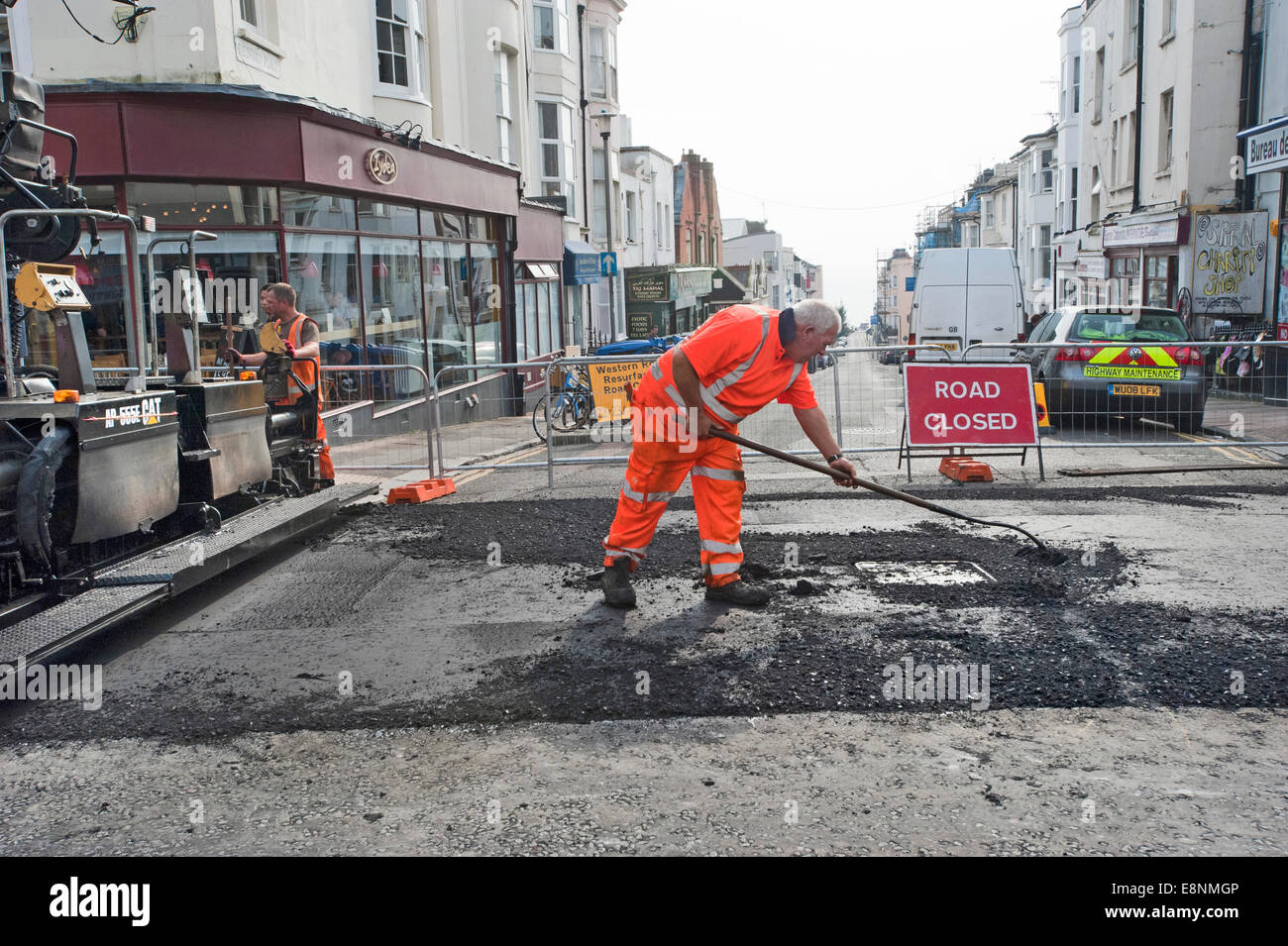 Eine Autobahn Wartung Worker flickt ein Schlagloch in einer Straße in Brighton. Stockfoto