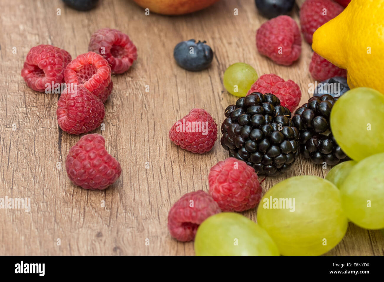 Zitrone, Trauben und Beeren Sommerfrüchte auf Holztisch Stockfoto