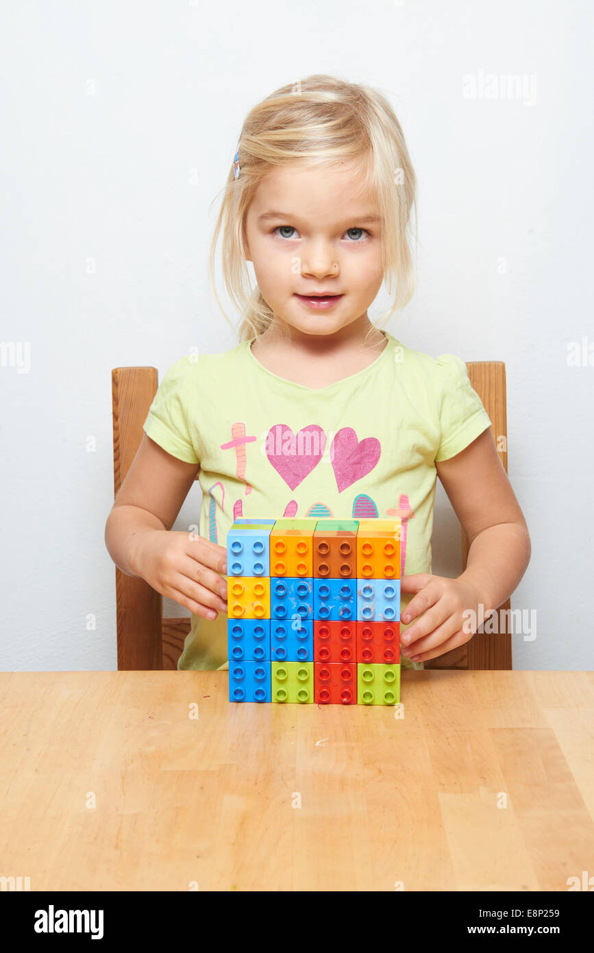Porträt von kleinen Kind blondes Mädchen spielen mit Kunststoff Bausteine, weißer Hintergrund Stockfoto