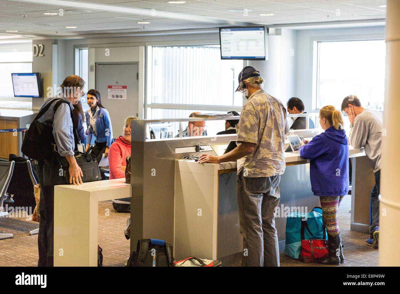 Menschen mit Steckdosen an die Macht Flug ihren elektronischen Geräten während des Wartens auf eine Abfahrt am terminal Stockfoto