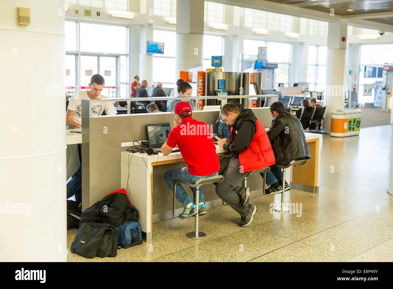 Menschen mit Steckdosen an die Macht Flug ihren elektronischen Geräten während des Wartens auf eine Abfahrt am terminal Stockfoto