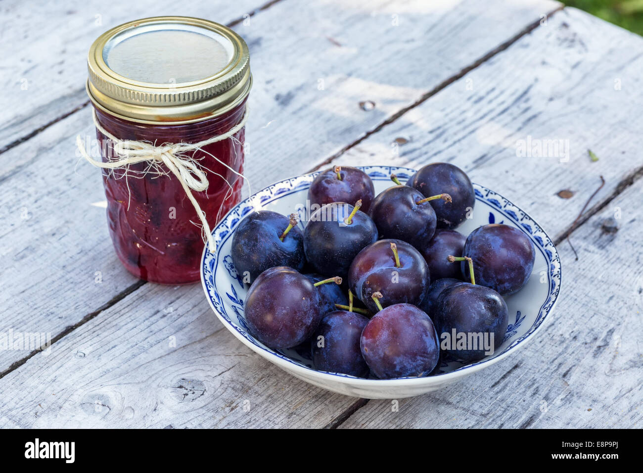 Hausgemachtes Pflaumenmus mit frisch gepflückt Pflaumen auf Holztisch Stockfoto