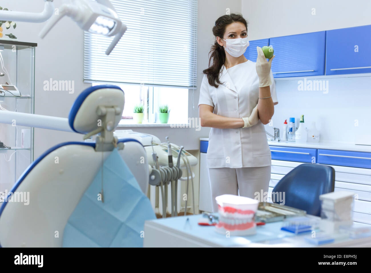 Zahnarzt Frau Maske Stomatologie Büro hält grünen Apfel. Health care Konzept Stockfoto