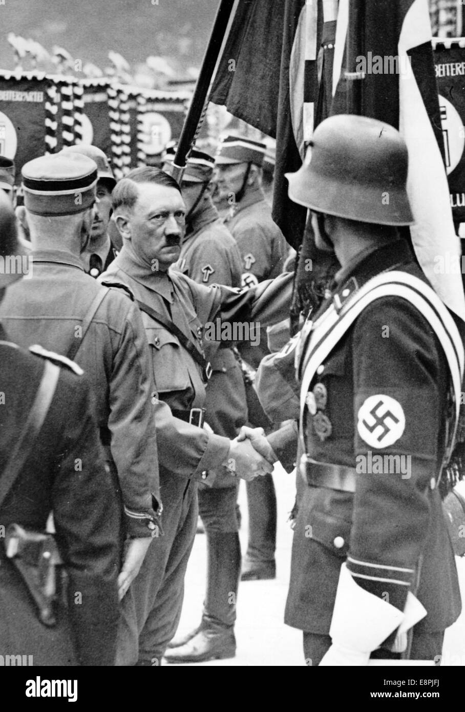 Nürnberger Rallye 1937 in Nürnberg – Adolf Hitler weiht die neuen Standards SA (Sturmabteilung), SS (Schutzstaffel) und NSKK (Nationales sozialistisches Kfz-Korps) mit der "Blutflagge" ein. Die neuen Standards werden von der "Blutflagge" (hinter Hitler) berührt, die angeblich während der Bierhalle Putsch getragen und damit geweiht wurde. Fotoarchiv für Zeitgeschichtee - KEINE ÜBERWEISUNG - Stockfoto