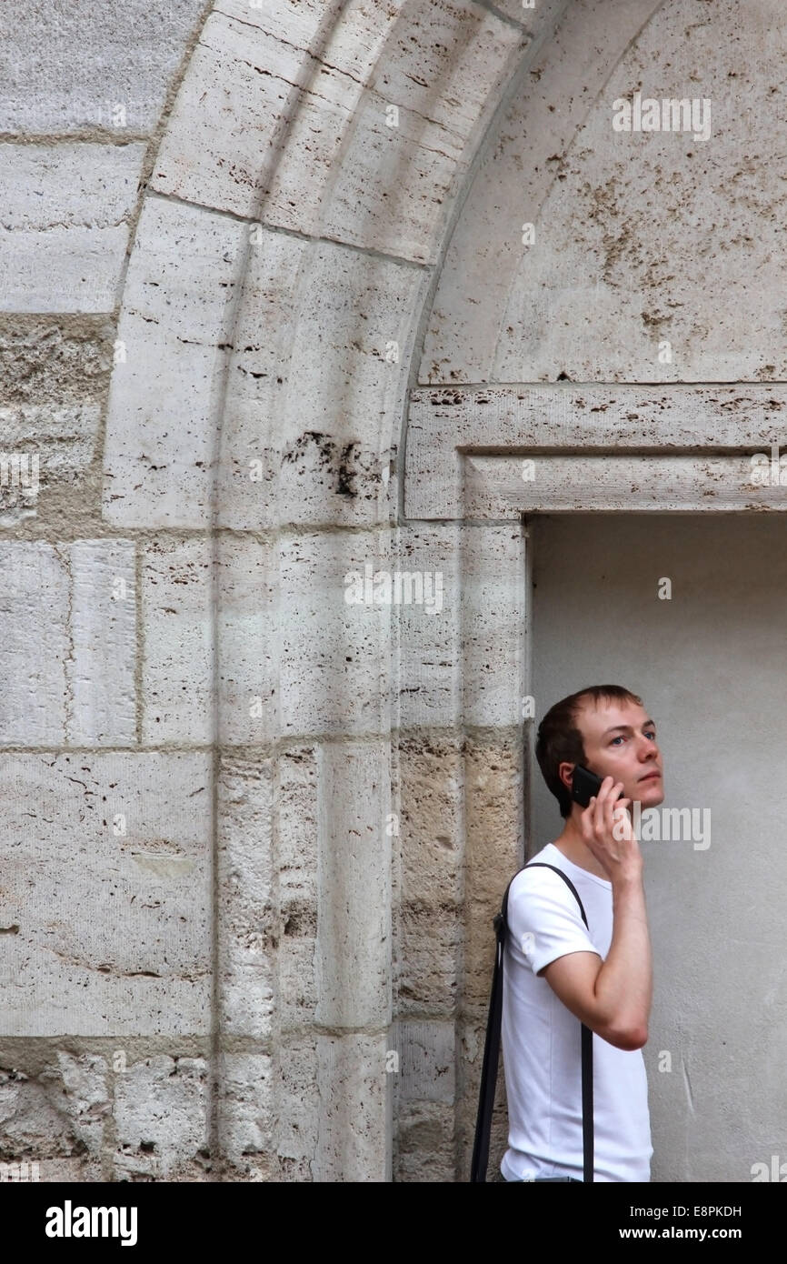 Junger Mann sprechen auf einem Handy in der Nähe von mittelalterlichen Steinmauer mit Bogen Stockfoto