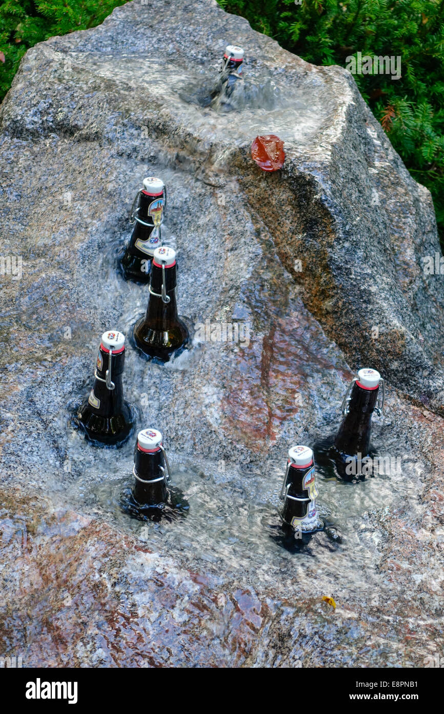 Bierflaschen werden in einem steinernen Brunnen gekühlt. Stockfoto