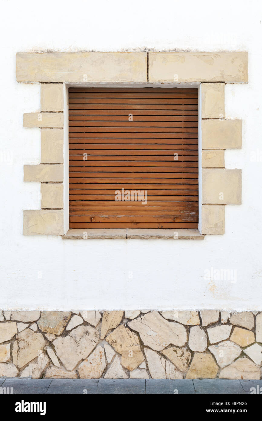 Alten weißen Steinmauer mit braunen hölzernen Fensterläden im Fenster. Hintergrundtextur Stockfoto