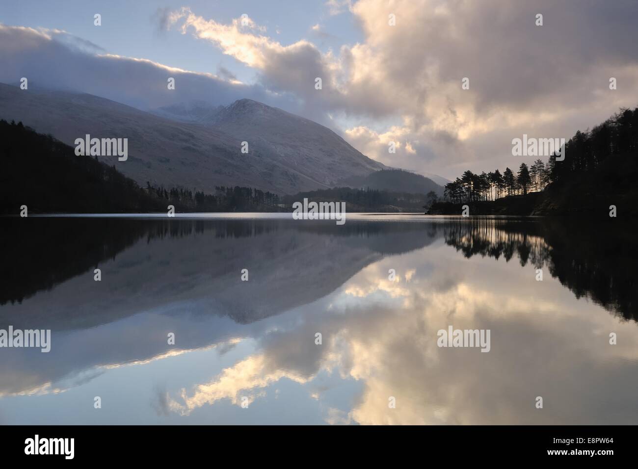 Kurz nach Sonnenaufgang zündete es Wolken durch die tief stehender Sonne zu reflektieren, in das Stille Wasser eines Sees in der Nähe von Keswick im Lake District. Stockfoto