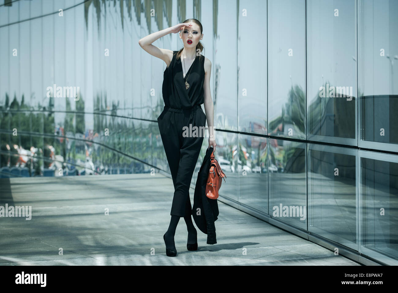 Schöne junge asiatische Geschäftsfrau mit Ledertasche um ein Glas-Bürogebäude Stockfoto