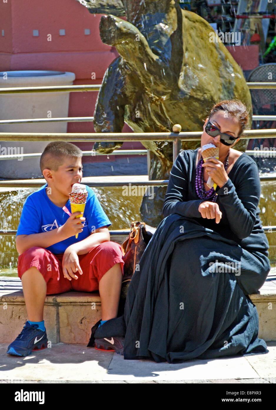 Mama und Sonne essen Eiscreme-Kegel am Einkaufszentrum Brunnen Stockfoto