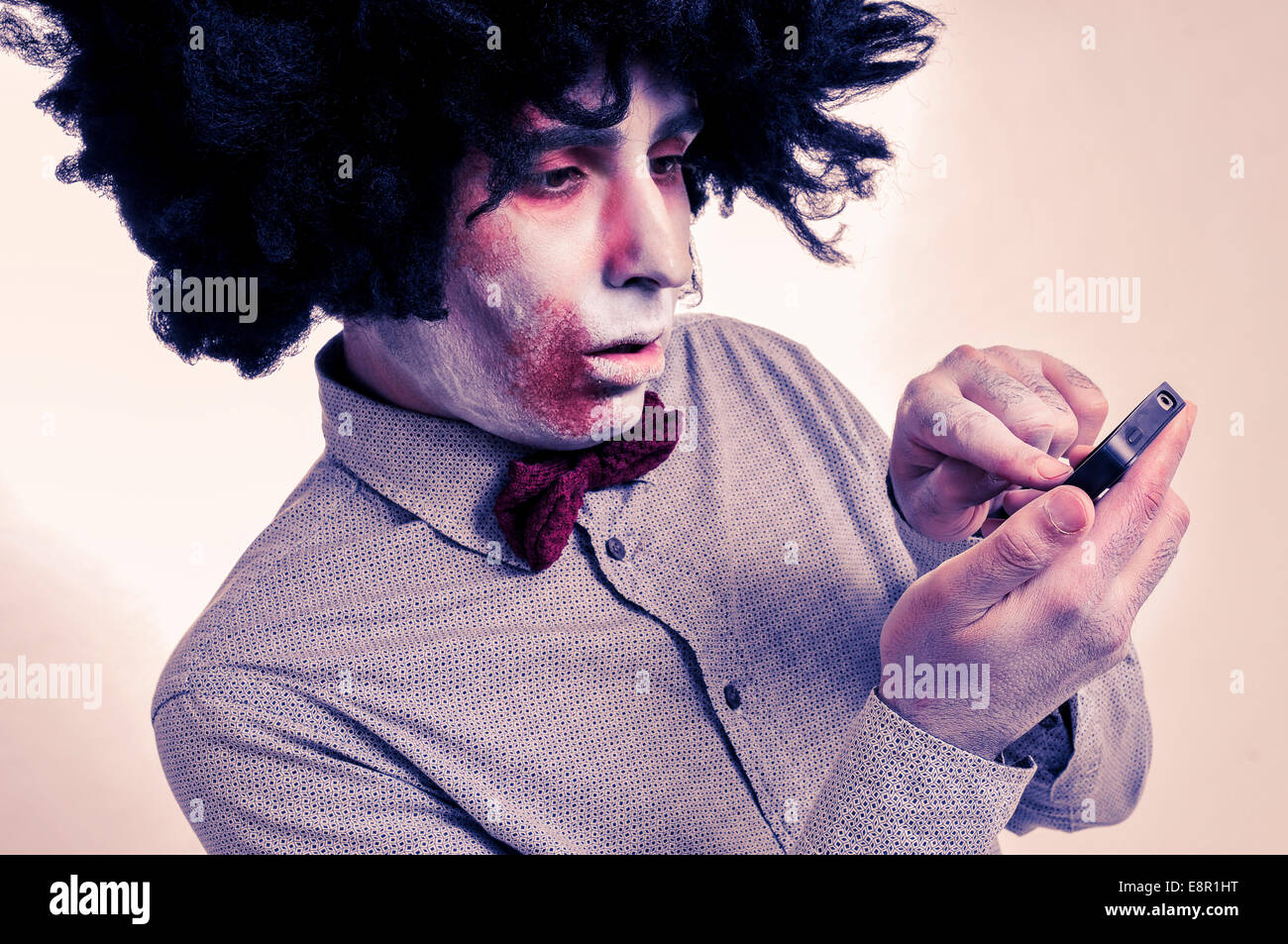 Hipster-Zombie mit einem Afro mit einem Smartphone mit einem Filtereffekt Stockfoto