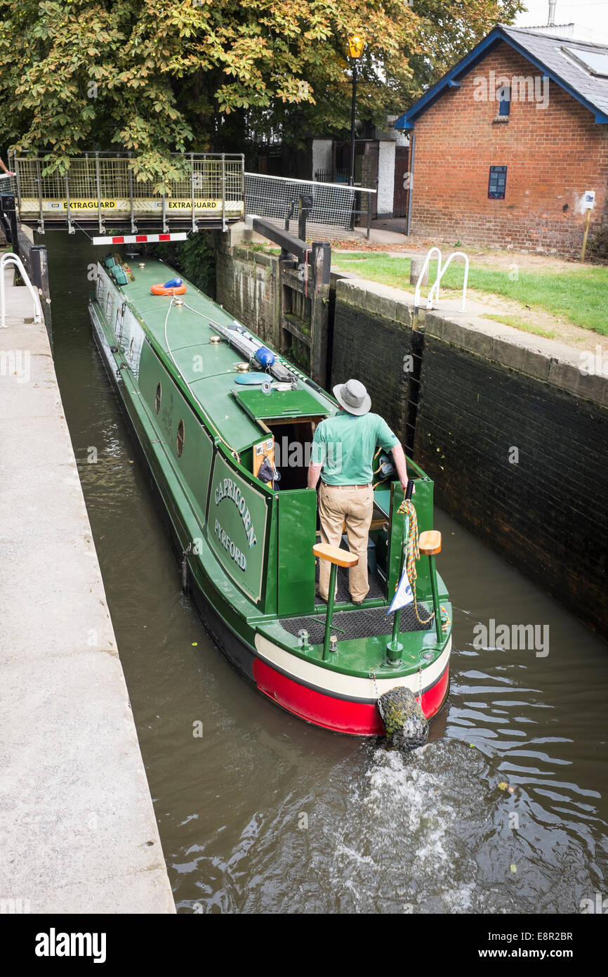 Mann hält die Pinne und stehen an der Spitze der ein Narrowboat verhandeln die Sperre für die Wey Navigation Canal in Guildford. Stockfoto