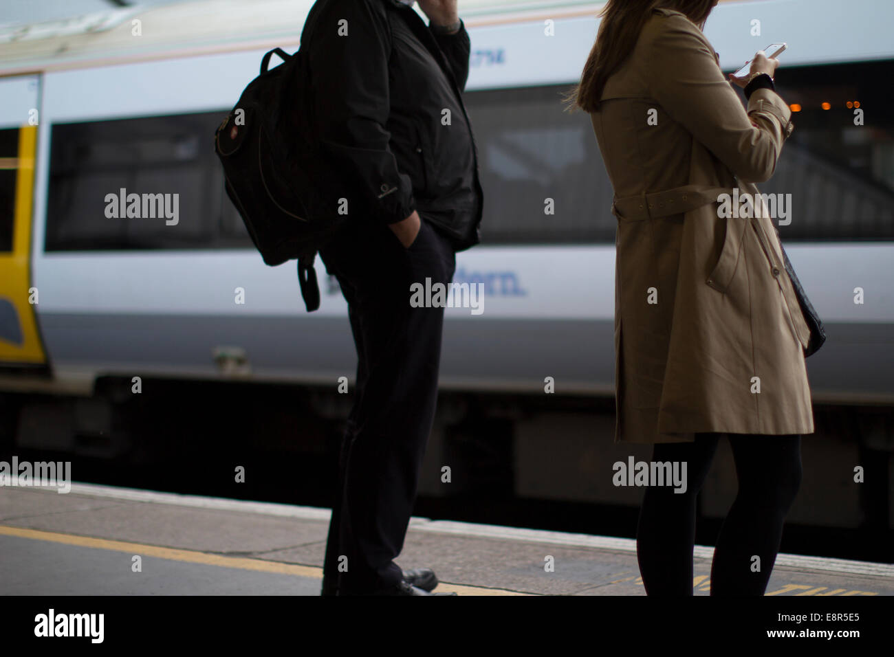 Passagiere warten auf Zug auf Handy in London Stockfoto