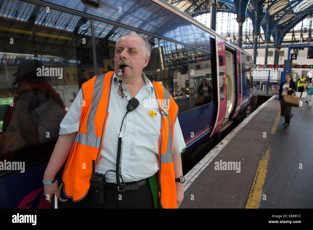 Ein Signal-Mann an einem Bahnhof statin bereitet seine Pfeife zu Blasen, um die Treiber wegzuziehen benachrichtigt. Bei Brighton Train Stat Stockfoto