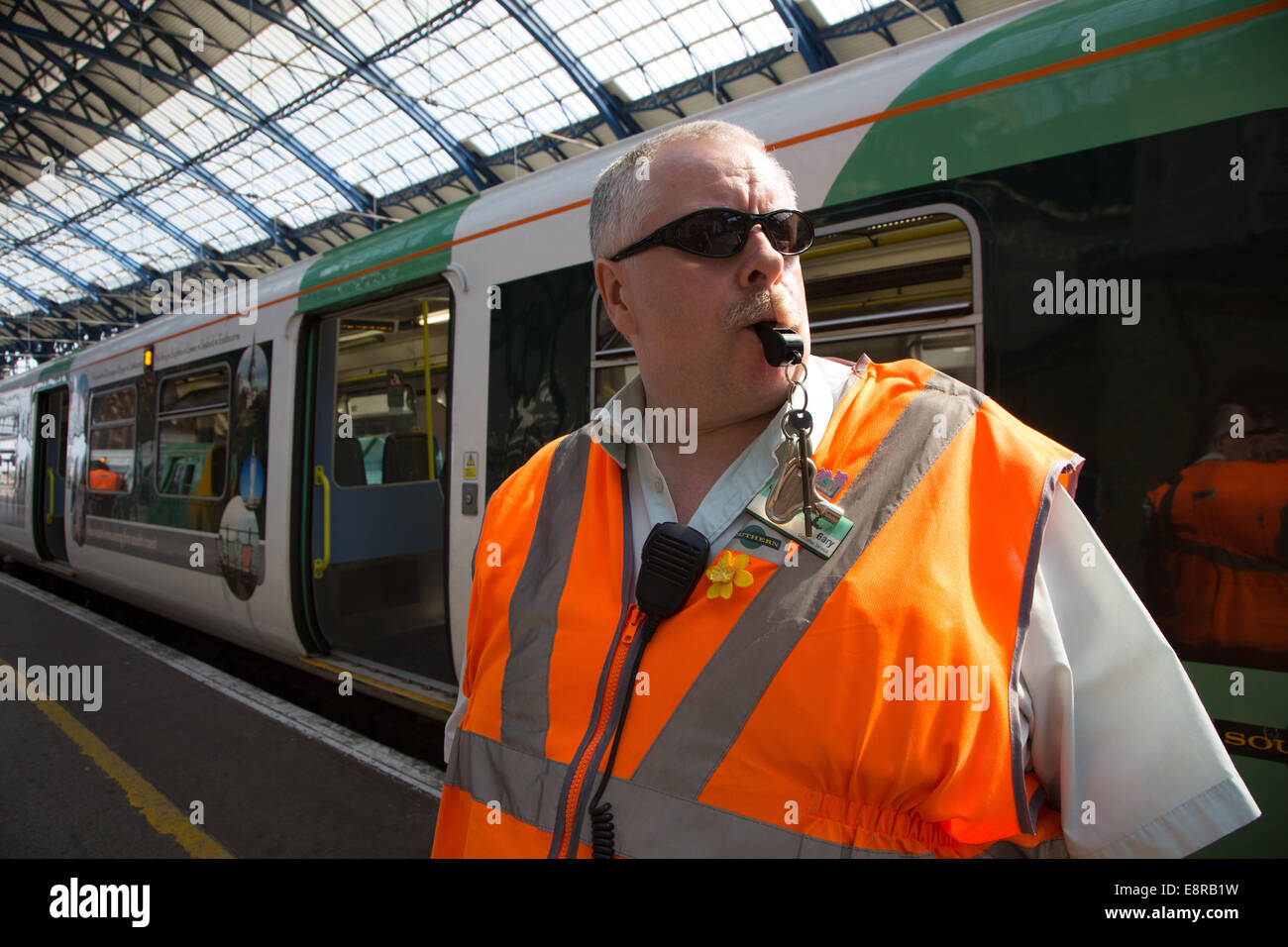 Ein Signal-Mann am Bahnhof von Brighton bereitet seine Pfeife zu Blasen, um die Treiber wegzuziehen benachrichtigt. Stockfoto