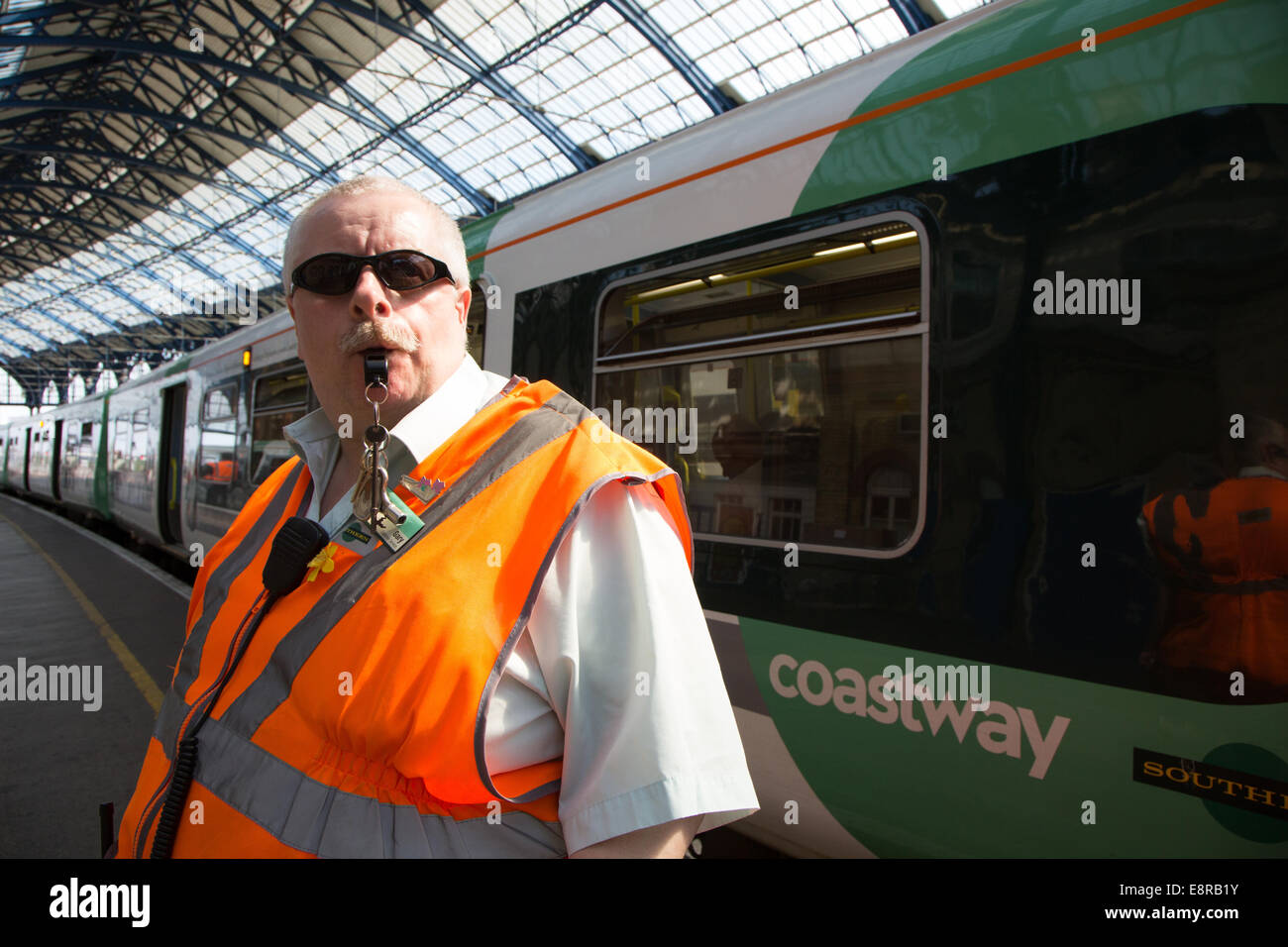 Ein Signal-Mann am Bahnhof von Brighton bereitet seine Pfeife zu Blasen, um die Treiber wegzuziehen benachrichtigt. Stockfoto