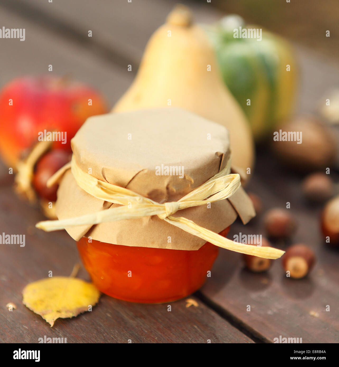 Kürbisse, Marmelade, Nüssen und Äpfeln auf Gartentisch Stockfoto