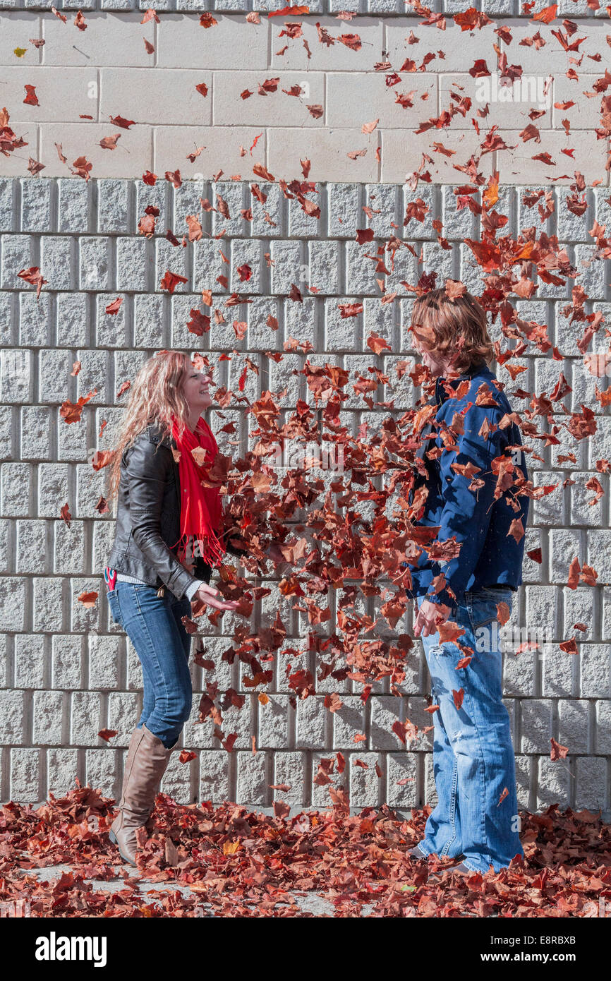 Nach Blätter über ihren Freund zu werfen, wie sie nach unten in den paar Kaskade lachende Frau Stockfoto