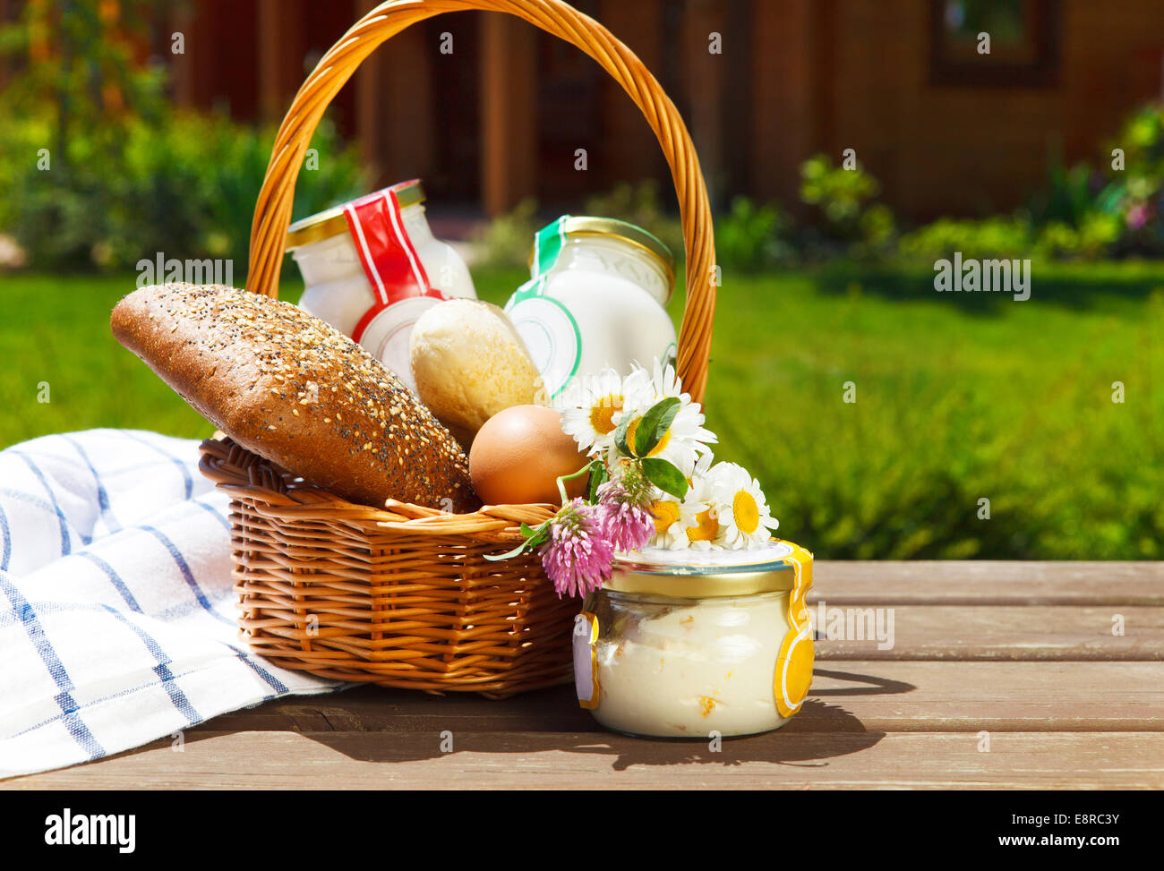 Verschiedene Milchprodukte: Käse, Sahne, Milch, Öl mit Brot, Eiern und Blumen. Auf einem Natur-Hintergrund Stockfoto