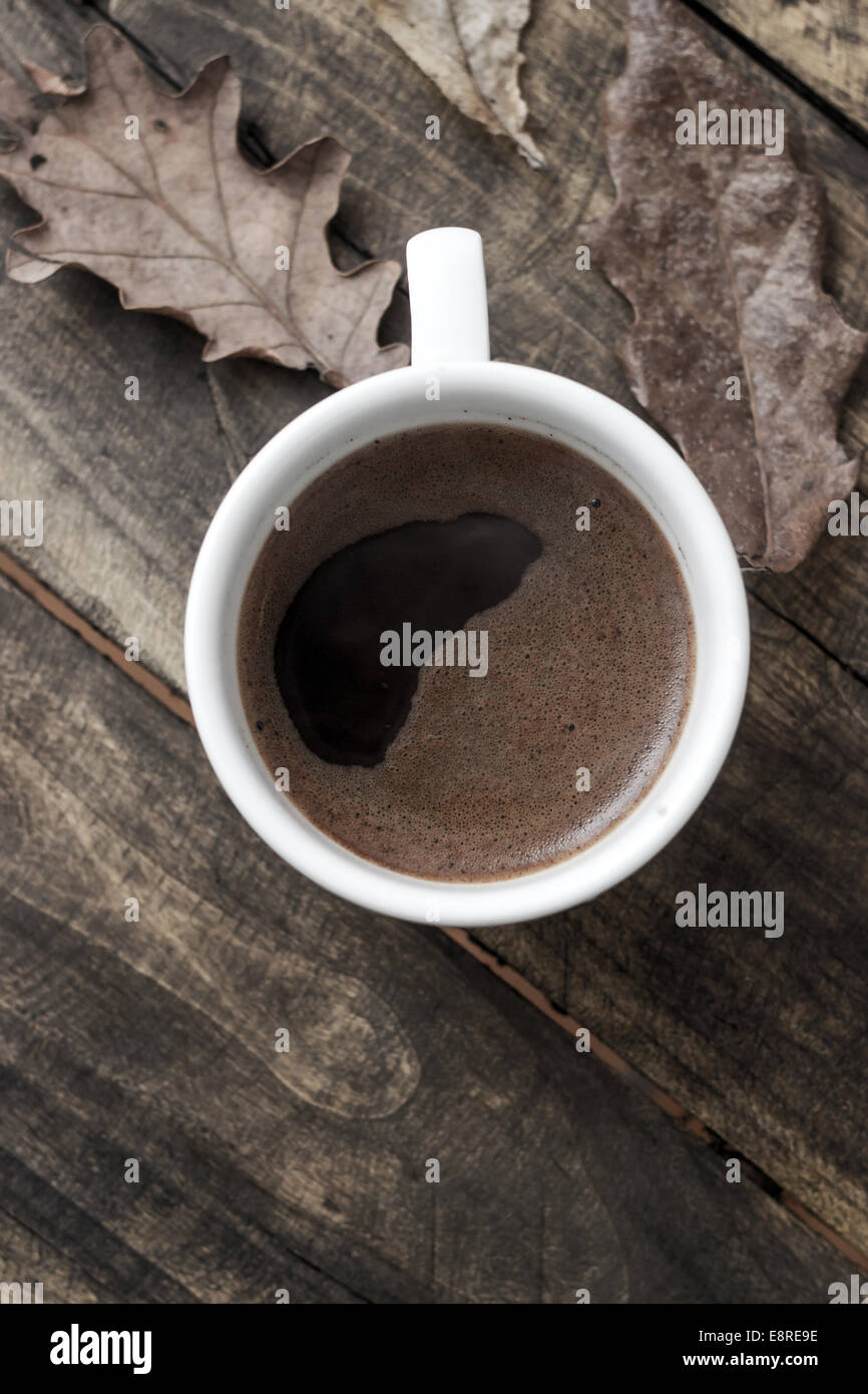 Kaffeetasse auf die Blätter im Herbst fallen und die hölzerne Oberfläche Hintergrund Stockfoto