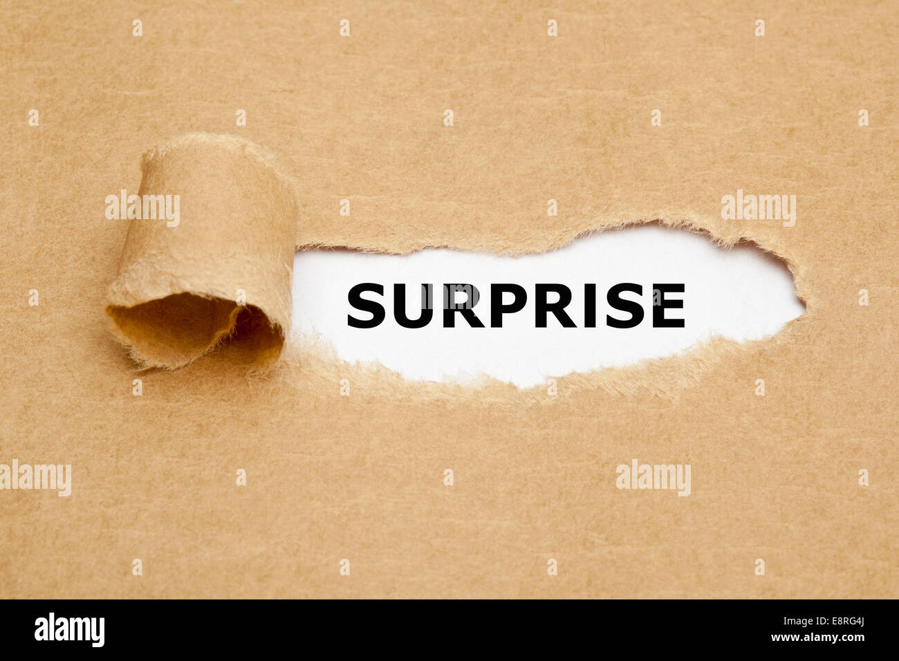 Das Wort Überraschung erscheint hinter zerrissenes braunen Papier. Stockfoto