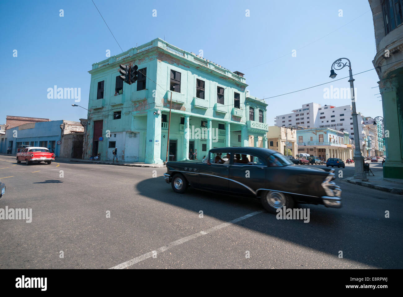 Zwei amerikanische Oldtimer Geschwindigkeit über eine Kreuzung in einem zentralen Viertel von Havanna. Stockfoto