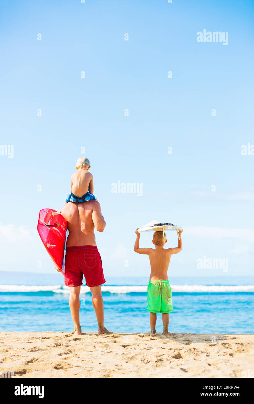 Vater und junge Söhne gehen surfen am Strand, mit Blick auf den Ozean Überprüfung der Wellen Stockfoto