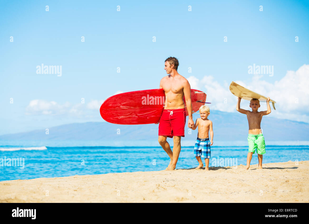 Vater und zwei Söhne gehen am Strand surfen Stockfoto