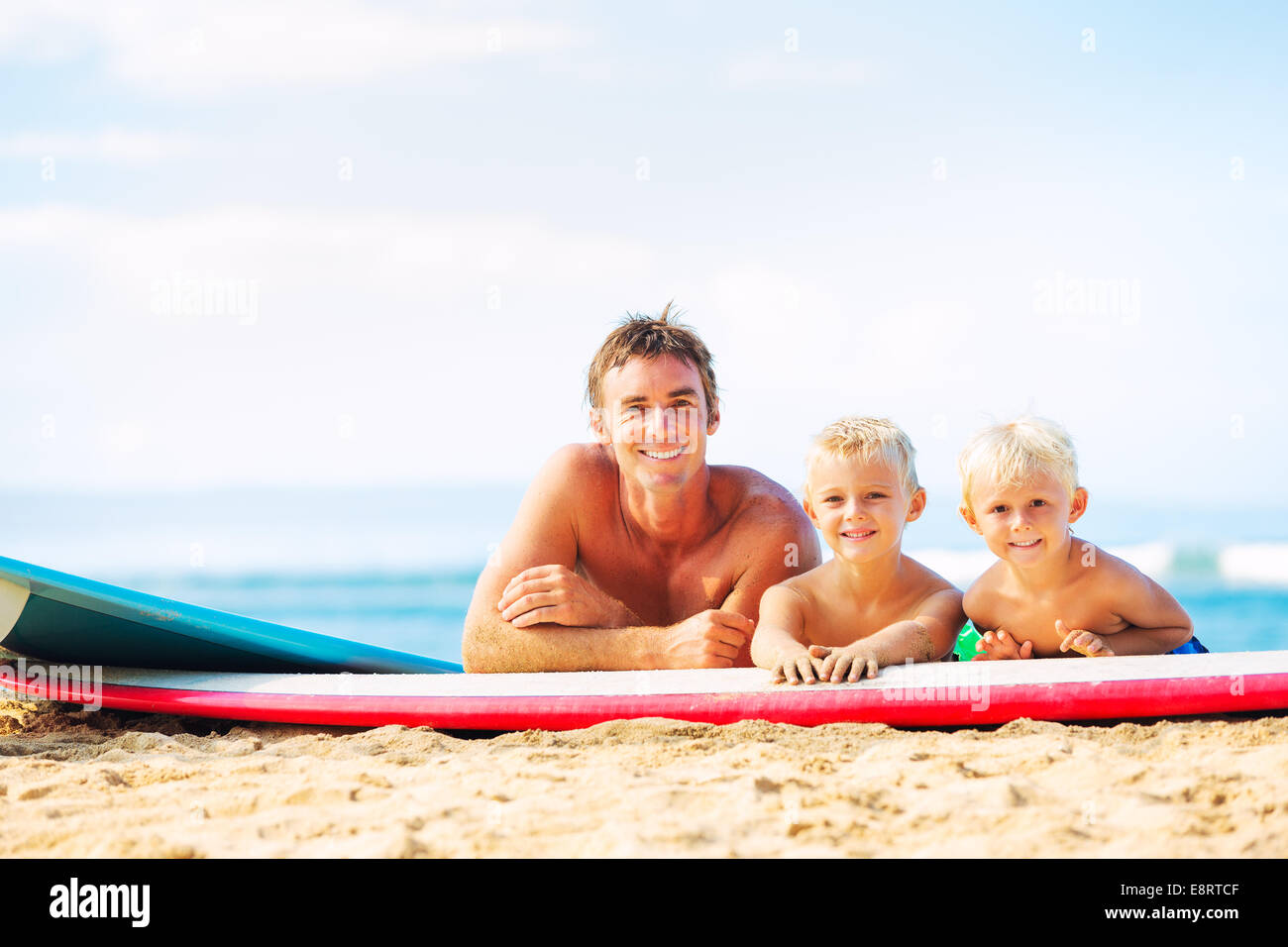 Vater und zwei Söhne gehen am Strand surfen Stockfoto