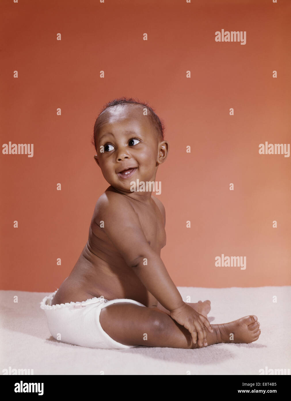 1970ER JAHREN AFRICAN AMERICAN BABY TRAGEN STOFFWINDEL RÜCKBLICKEND ÜBER DIE SCHULTER Stockfoto