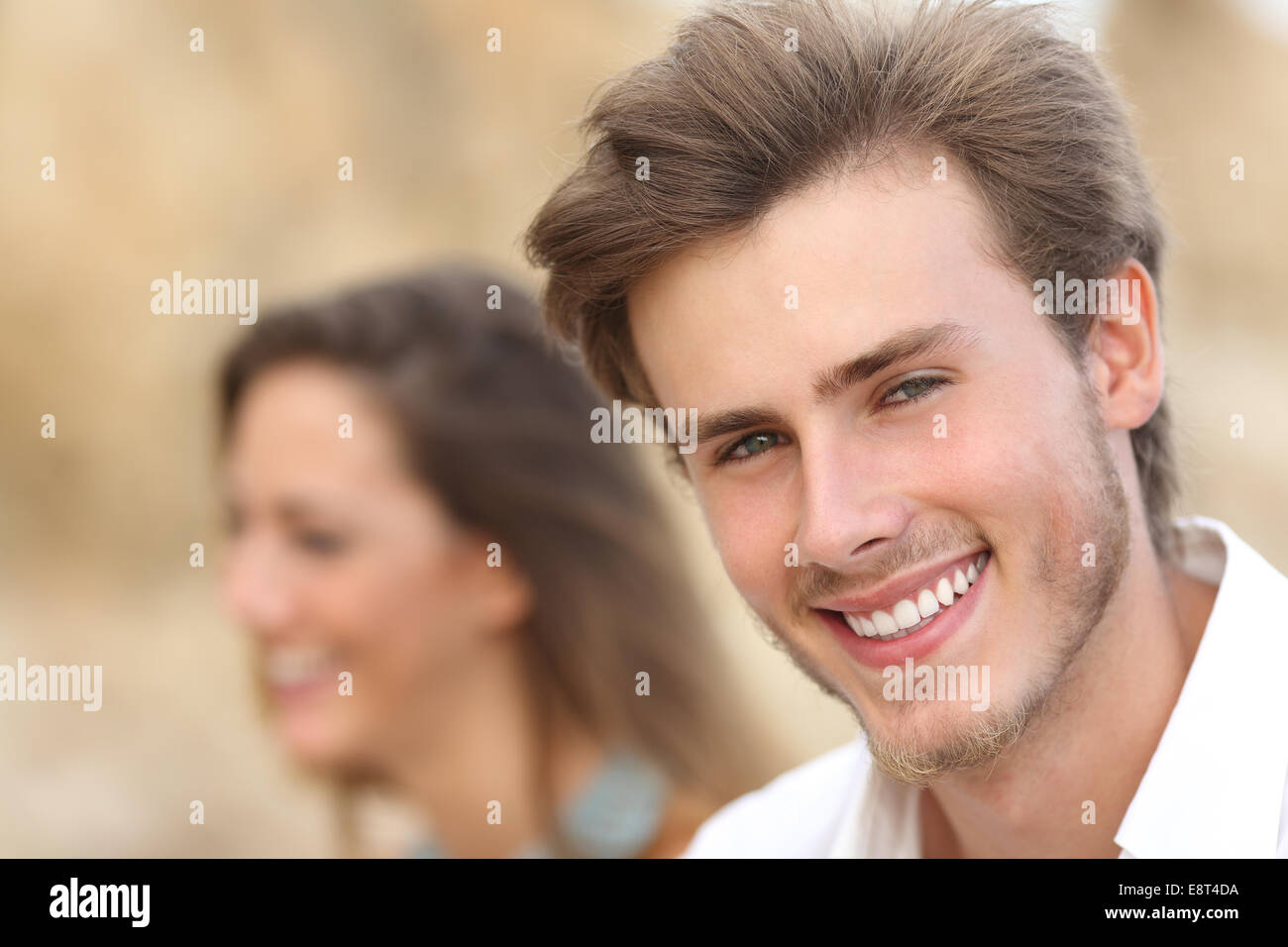 Gut aussehender Mann Nahaufnahme Portrait mit einem perfekten weißen Zahn und Lächeln mit einem Mädchen im Hintergrund Stockfoto