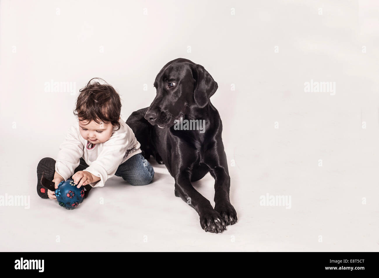 Große schwarze Promenadenmischung liegen neben einem kleinen Kind Stockfoto
