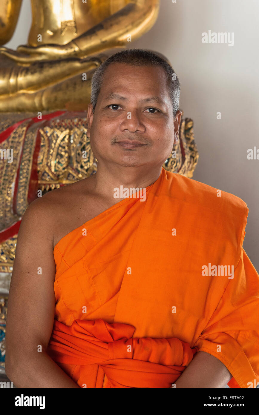 Thailändischer buddhistischer Mönch in der Nähe von Statue lächelnd Stockfoto