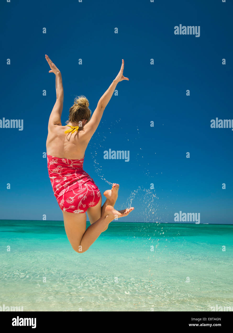 Kaukasische Frau springen vor Freude im tropischen Ozean Stockfoto