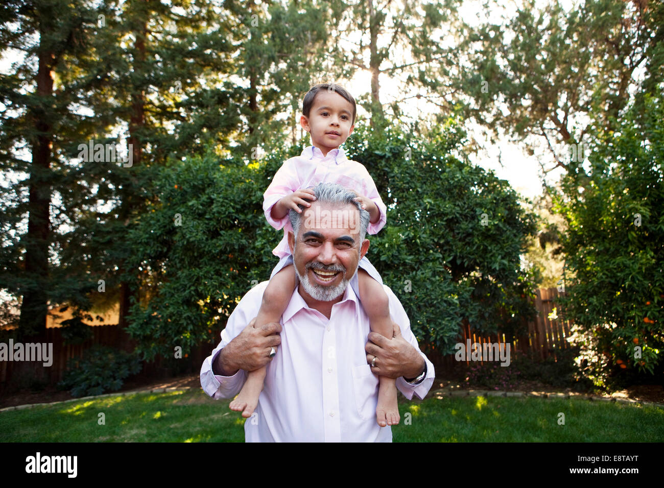 Großvater mit Enkel auf Schultern im Hinterhof Stockfoto