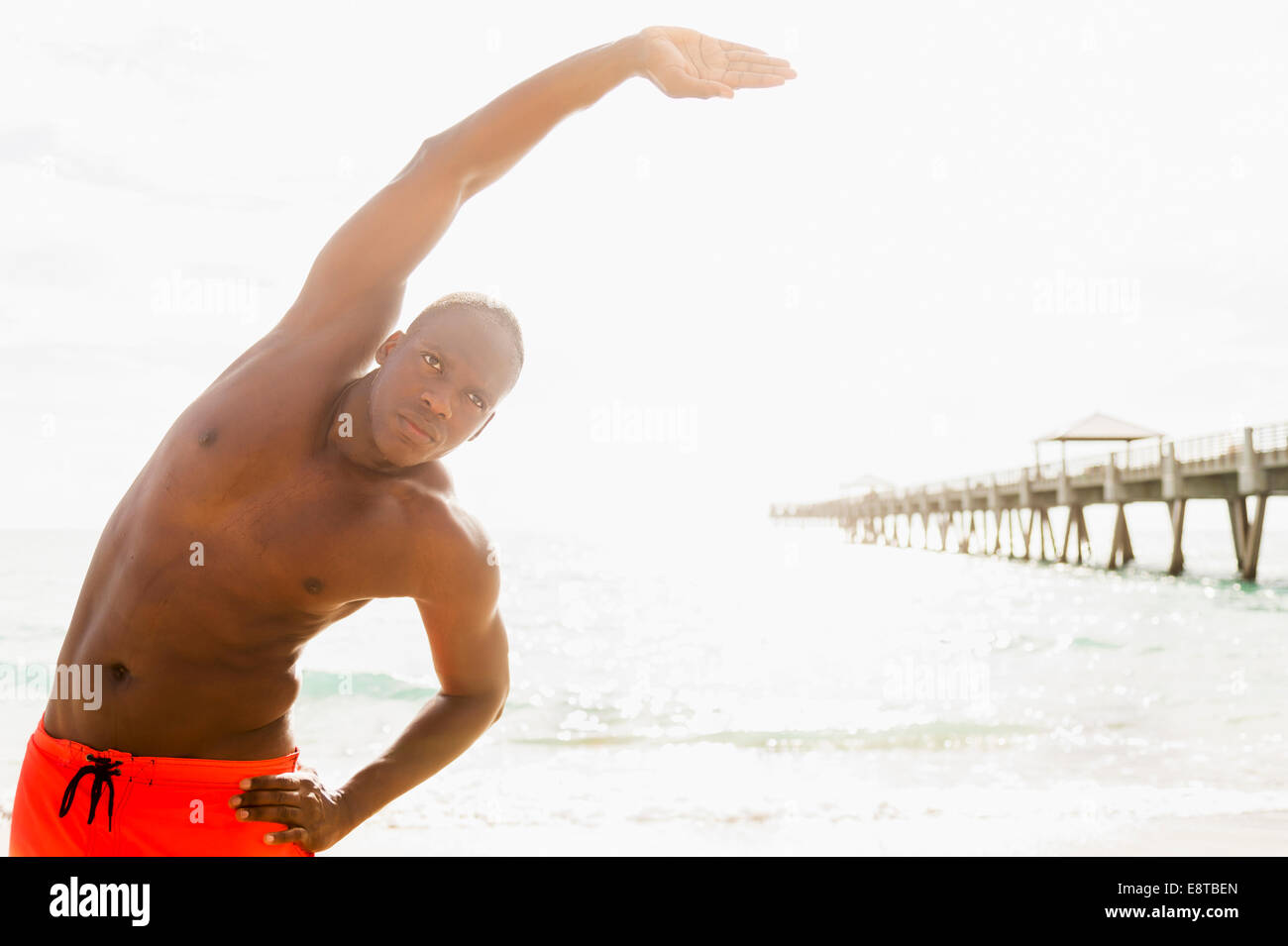 Gemischte Rassen Mann stretching am Strand Stockfoto