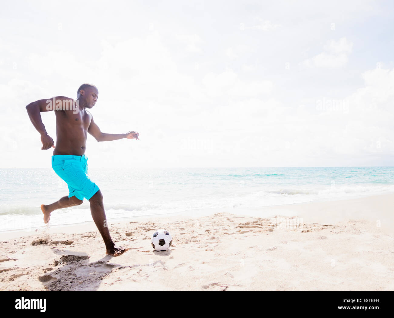 Gemischte Rassen Mann spielt mit Fußball am Strand Stockfoto