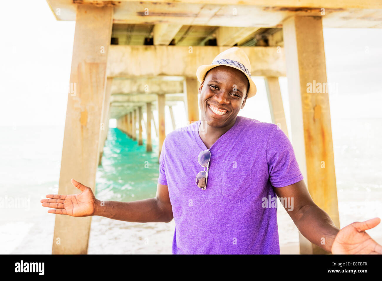 Gemischte Rassen Mann lächelnd unter Pier am Strand Stockfoto