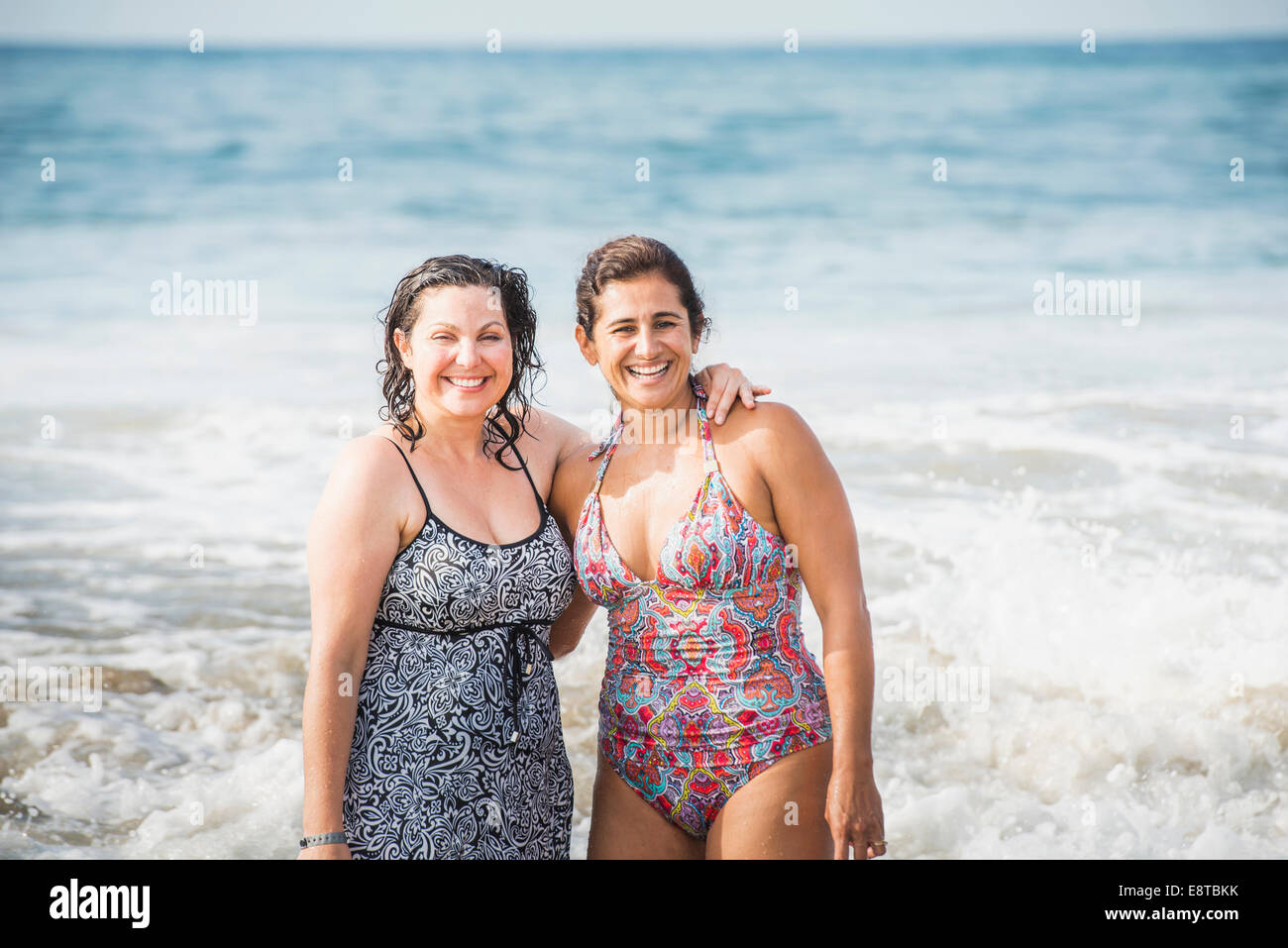 Frauen Lächeln zusammen in Wellen des Ozeans Stockfoto