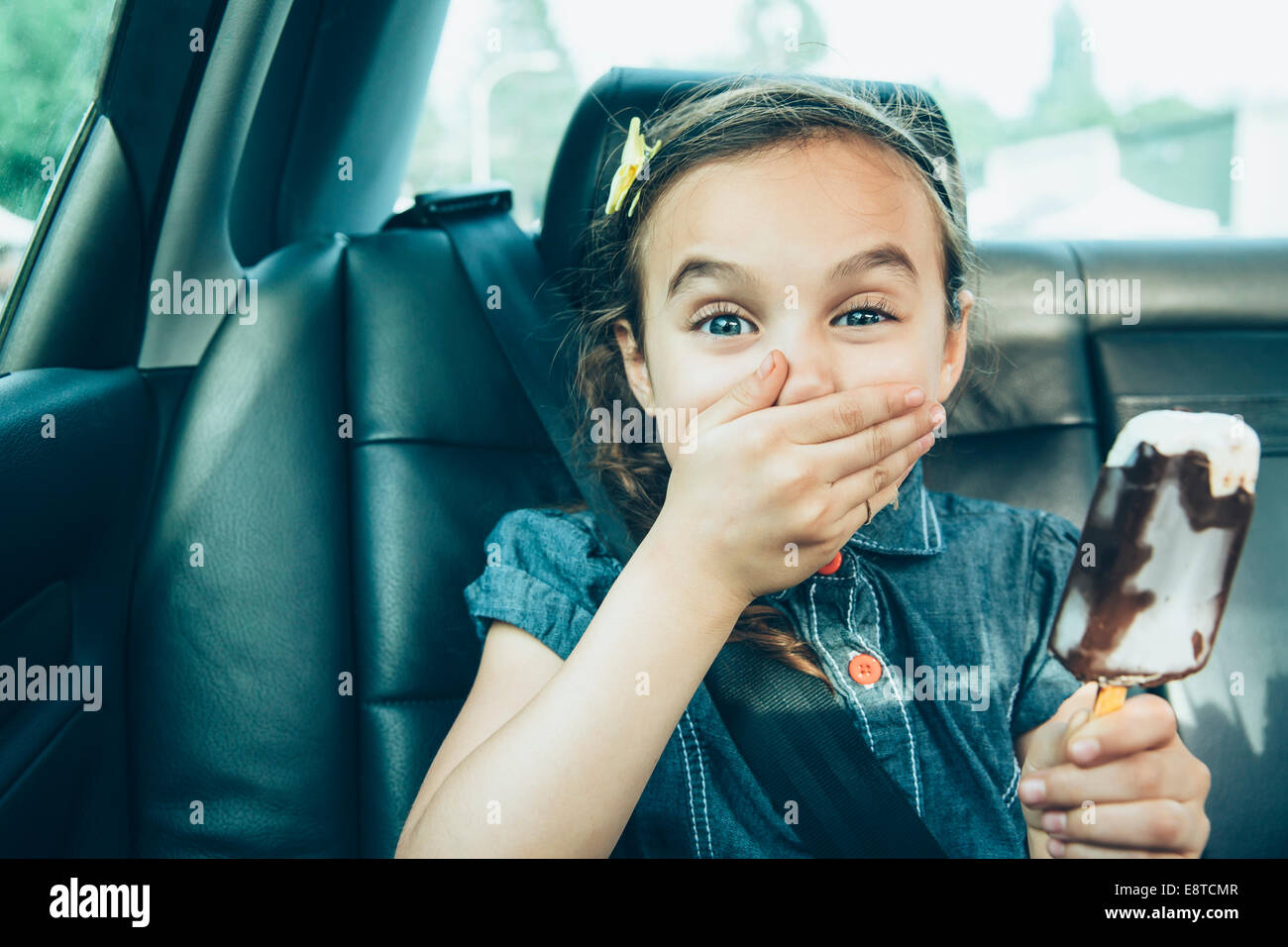 Gemischte Rassen Mädchen essen Eisbar auf dem Auto Rücksitz Stockfoto