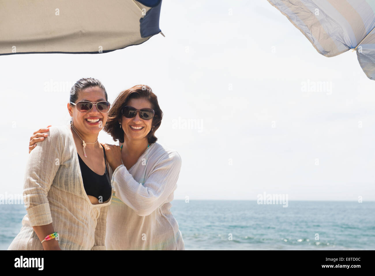 Hispanische Frauen Lächeln zusammen am Strand Stockfoto