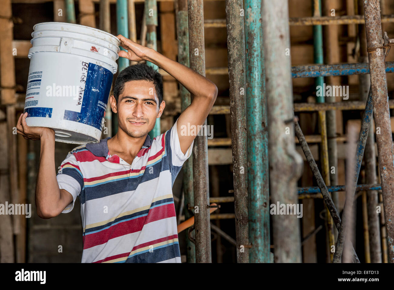 Hispanische Bauarbeiter tragen Eimer auf Baustelle Stockfoto