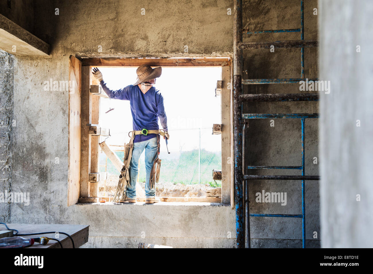 Hispanische Bauarbeiter im Fenster auf Baustelle Stockfoto