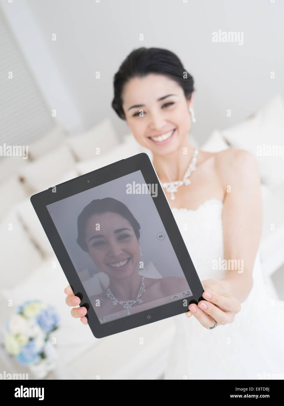 Mischlinge, asiatische / American Braut im weißen Hochzeitskleid unter Selfie mit einem Apple iPad. Stockfoto