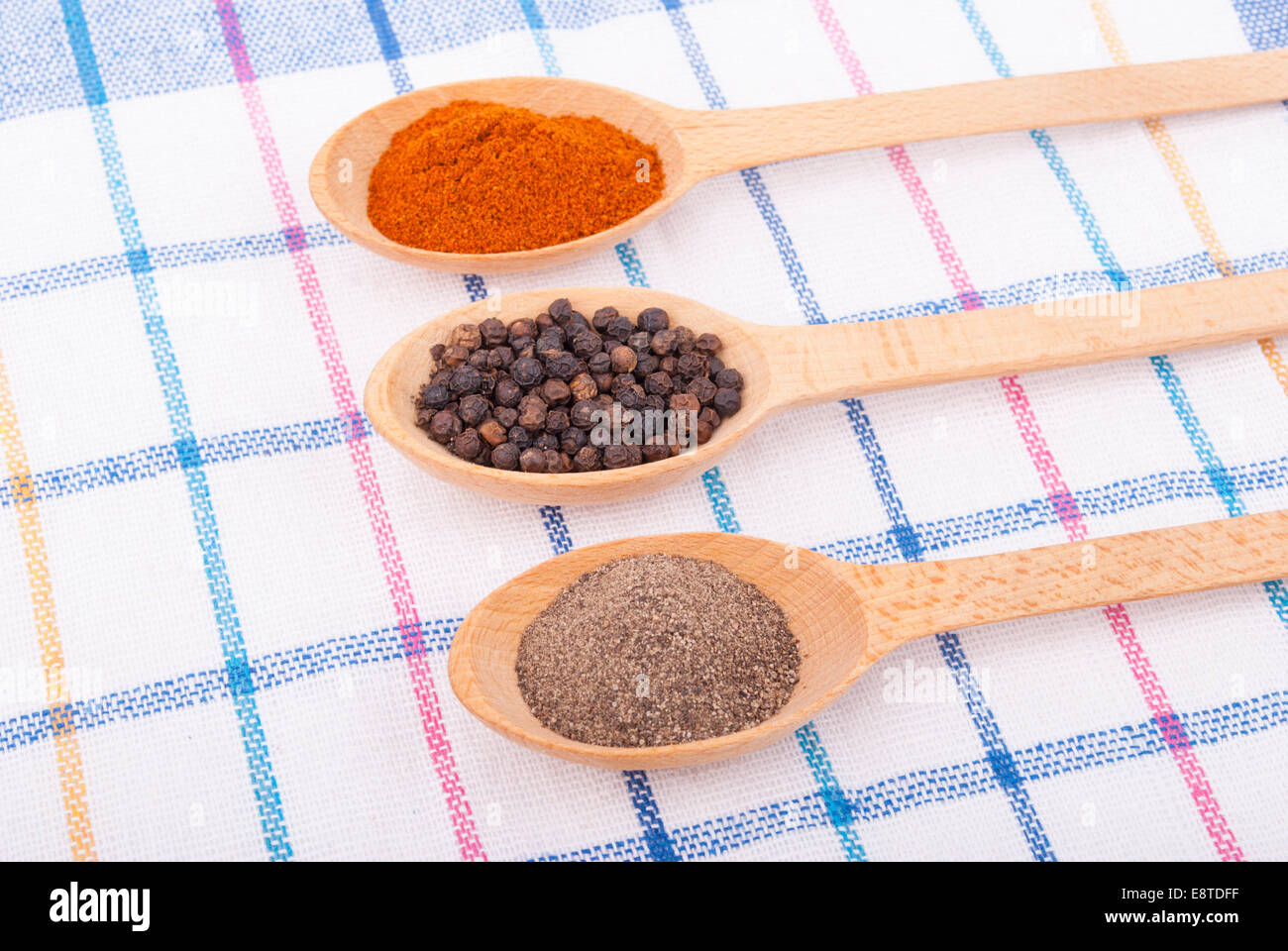 Ganz und gemahlen Pfeffer in einem Holzlöffel auf der Tischdecke. Stockfoto